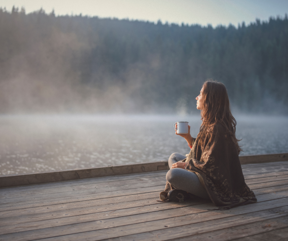 woman sitting outside holding a glass of water, enjoying a peaceful moment in the morning sun.